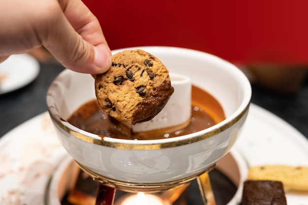 Hand holding cookie chocolate chip with chocolate sauce