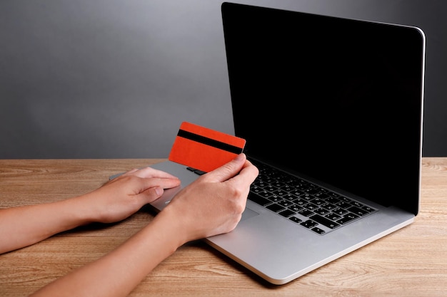 Hand holding credit card to buy online on gray background