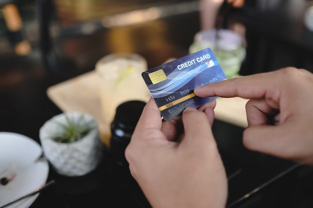 Hand holding credit card in cafe.