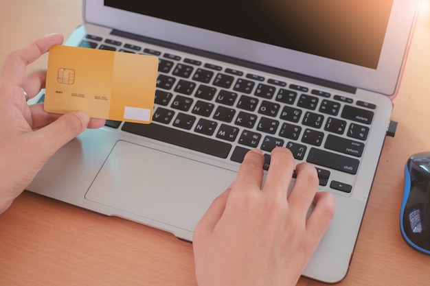 Hand holding a credit card and entering data into a computer laptop