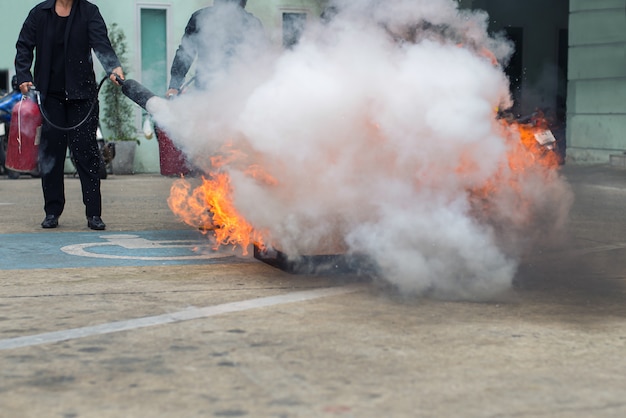 Hand holding fire extinguisher and spraying to the burning fire