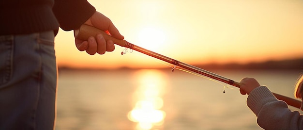 a hand holding a fishing pole with the sun behind it