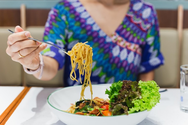 Hand holding fork eating spaghetti in restaurant