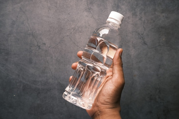 Hand holding of fresh drinking water bottle against black background