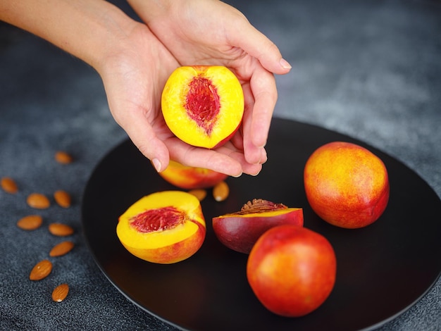 Photo hand holding fresh peach fruit and black dish