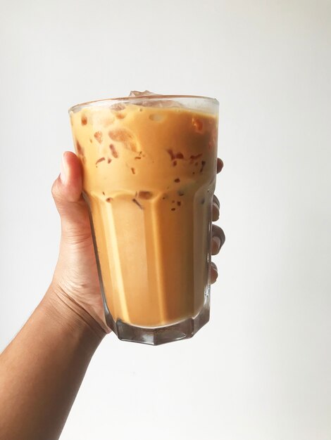 Hand holding the glass of cold coffee with white background