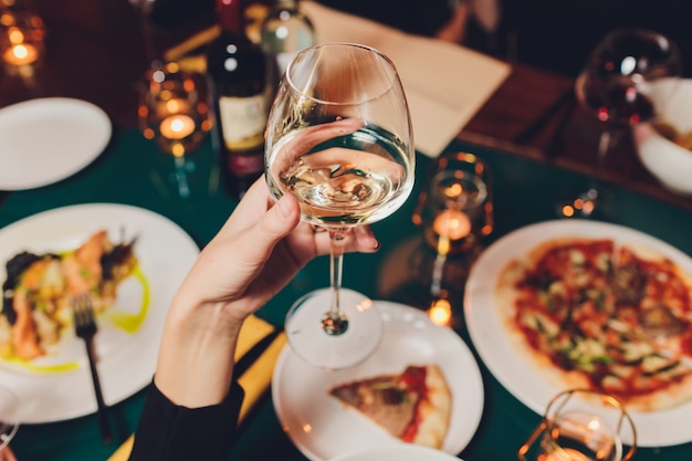 Hand holding a glass above table with food