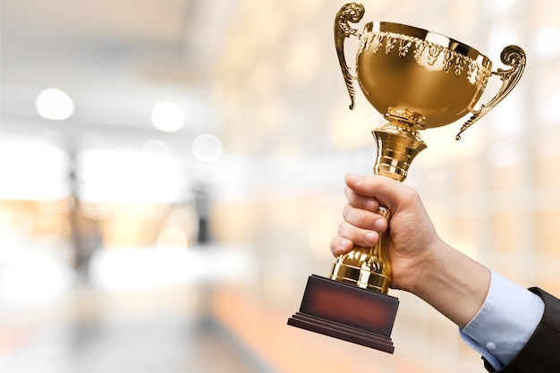 Hand holding golden trophy on blurred background