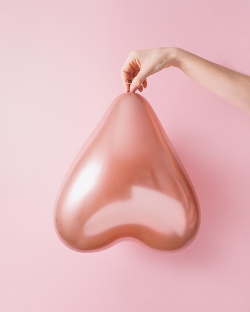 Hand holding hologram balloon in the shape of a heart Minimal love or female womans day concept