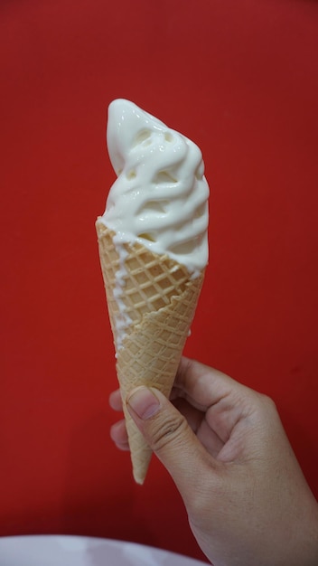 Hand Holding Ice Cream Against PeacockColored Wall