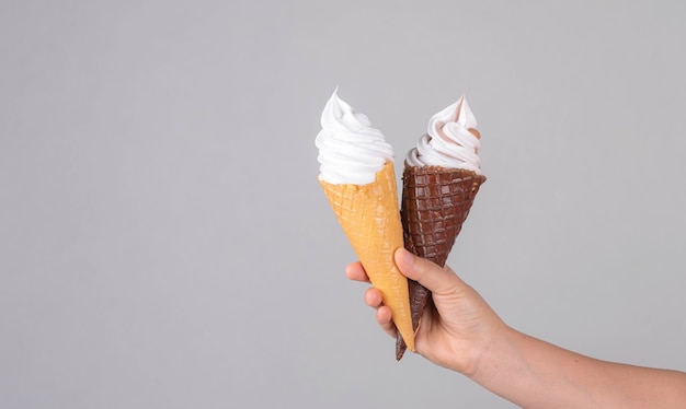 Hand holding ice cream in waffle cone against color background