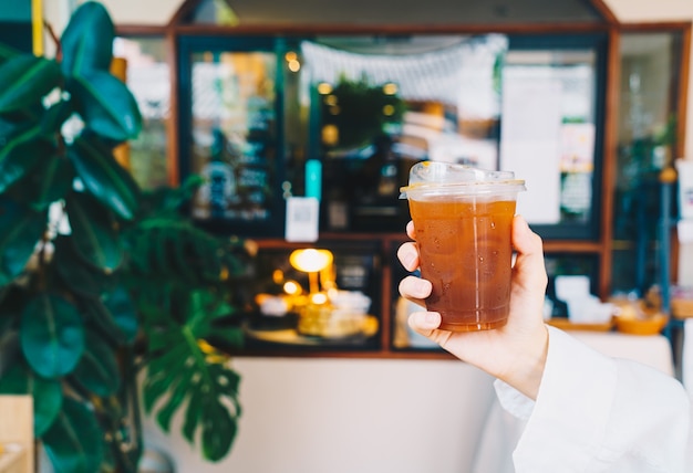 hand holding iced americano coffee in takeaway glass