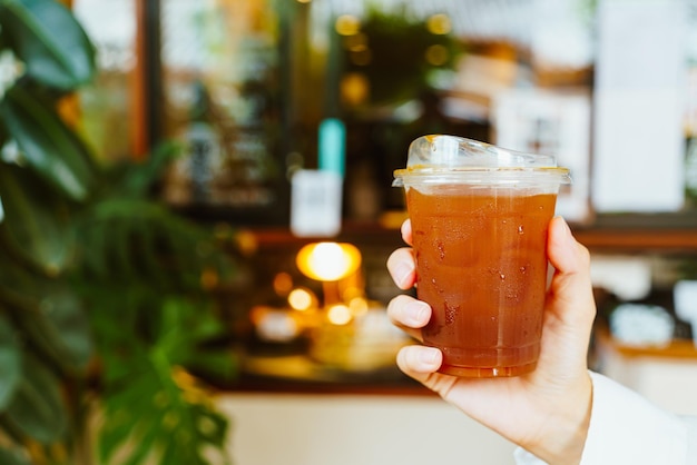 hand holding iced americano coffee in takeaway glass