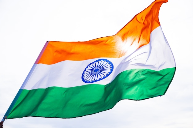 hand holding India flag on the blue sky background. Indian Independence Day, 15 August.