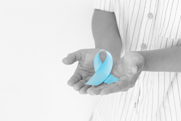 Hand holding Light blue color ribbon on white isolated background Prostate Cancer Awareness