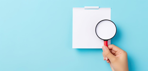 a hand holding a magnifying glass over a blank white paper