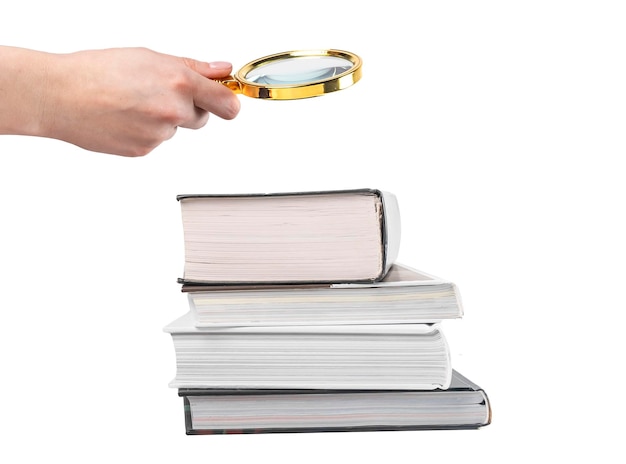 Hand holding magnifying glass over books stack isolated on white background Research and detailed study of information concept High quality photo