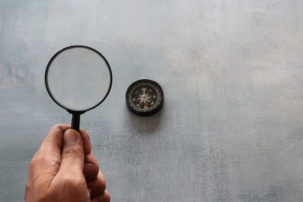 Hand holding magnifying glass and compass Looking for direction and guidance concept