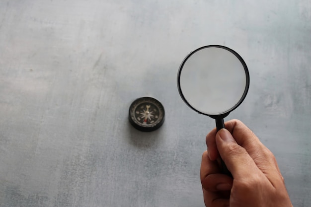 Hand holding magnifying glass and compass Looking for direction and guidance concept