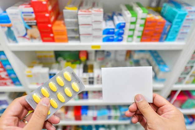 Hand holding medicine with note pad on Shelves blurred in pharmacy store