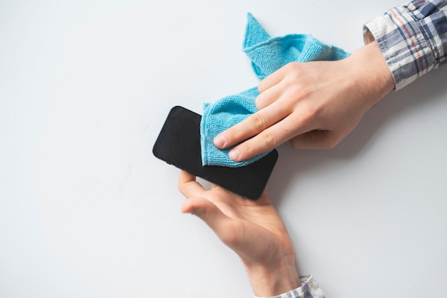 A hand holding a microfiber napkin and wipe the dirty smartphone screen