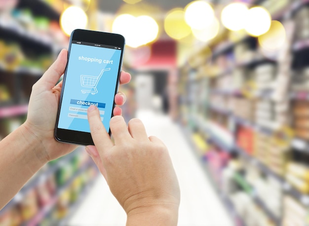 Hand holding a modern smartphone in supermarket