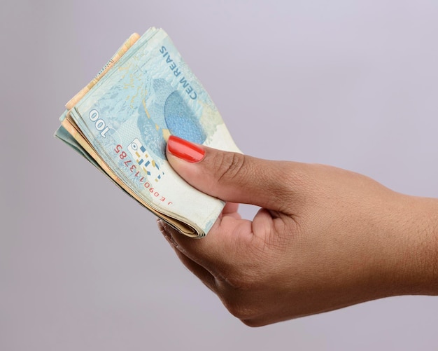 Hand holding money six hundred reais Brazilian currency on white background