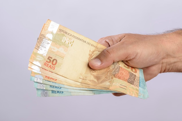 Hand holding money six hundred reais Brazilian currency on white background