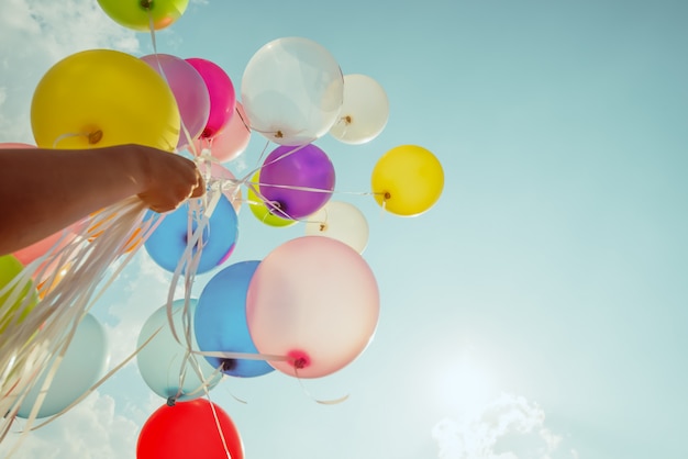 Photo hand holding multi colored balloons