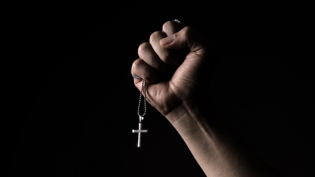 Hand holding a necklace with a cross pendant