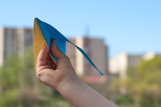 Hand holding the paper flag painted in colors of Ukrainian yellowblue flag Support Ukraine in war