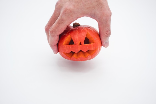 A hand holding a pumpkin on a white background. Pumpkin on a white background. Halloween pumpkin.