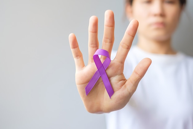 Hand holding purple Ribbon for Pancreatic, Esophageal, Testicular cancer, world Alzheimer, epilepsy, lupus, Sarcoidosis, Fibromyalgia and domestic violence Awareness month. World cancer day concept