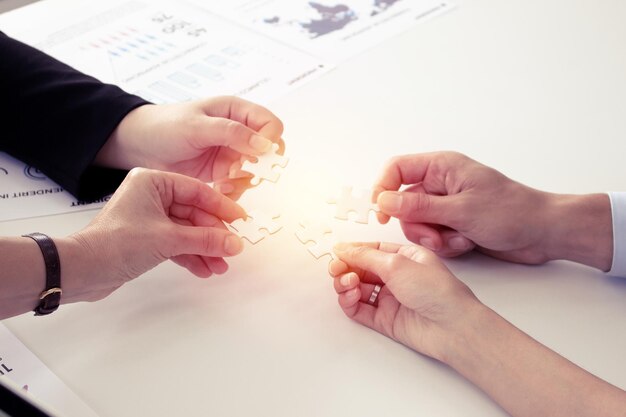 Hand holding the puzzles for the businessmen to work together as a team. Concept of planning work as a teamwork. Closeup of businesspeople holding jigsaw puzzle.