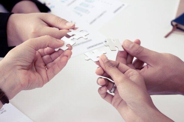 Hand holding the puzzles for the businessmen to work together as a team. Concept of planning work as a teamwork.