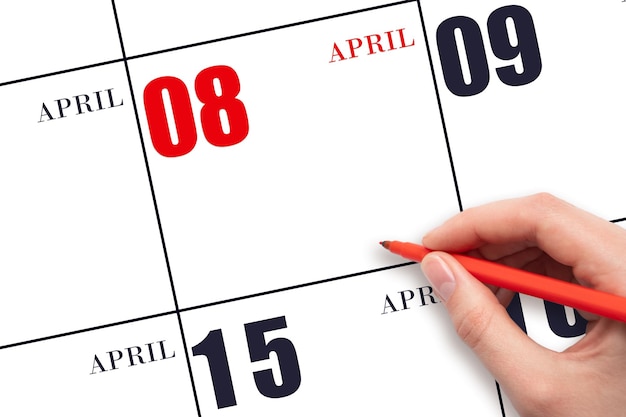 A hand holding a red pen and pointing on the calendar date April 8 Red calendar date copy space mockup