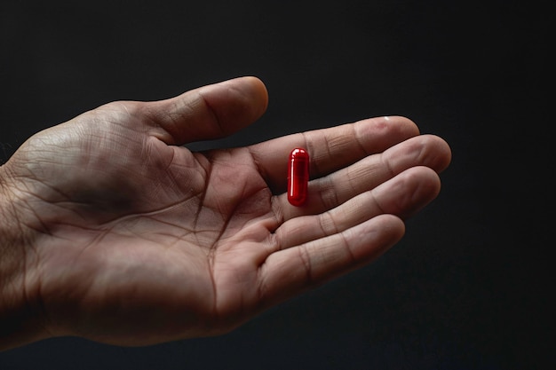 a hand holding a red pill