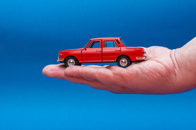 Hand holding red toy car isolated on blue background