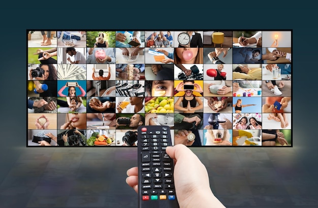 Photo a hand holding a remote control in front of a television