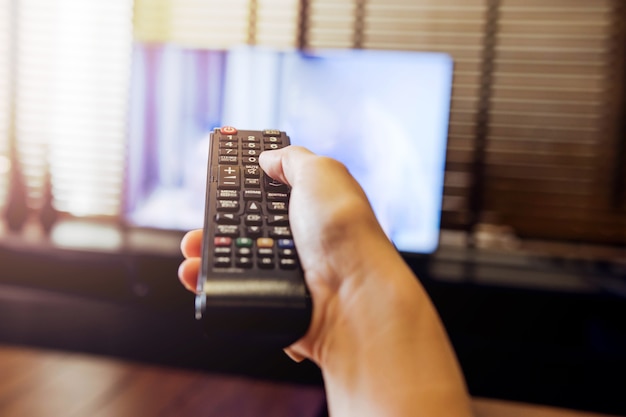 Hand Holding Remote Control and Watching TV