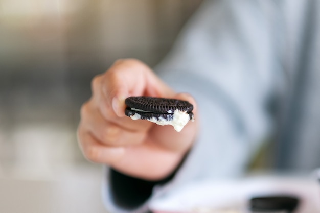 A hand holding and showing chocolate biscuit with whip cream