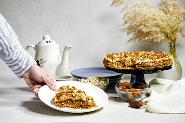 hand holding a slice of a Homemade Russian Honey dates and peanuts cake Honey cake Medovik