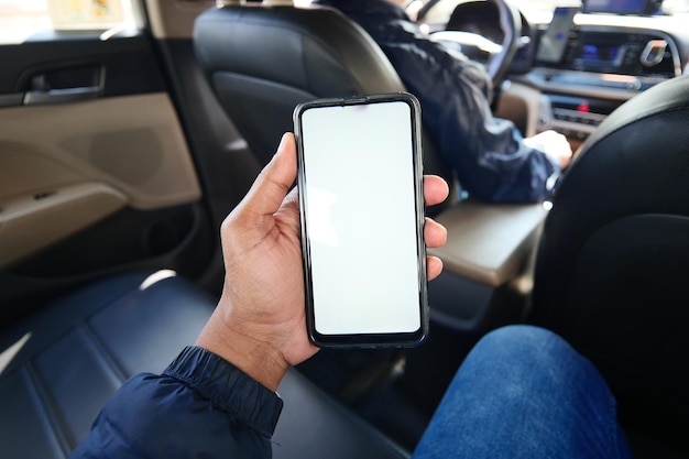 Hand holding smart phone with empty screen in a car