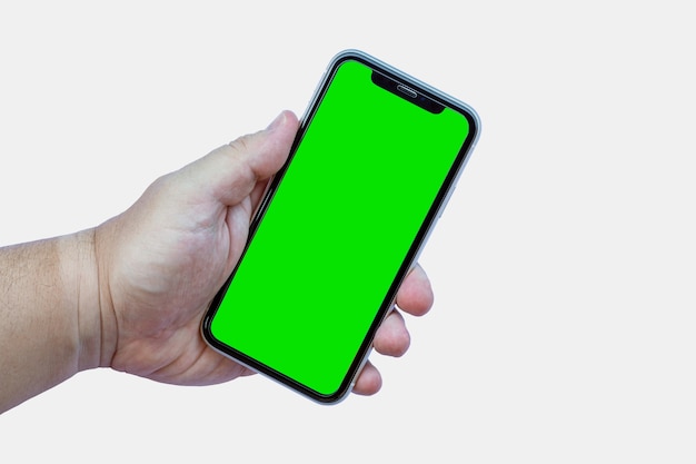 Hand holding a smartphone connected from the front with green screen on white background. Selective focus.