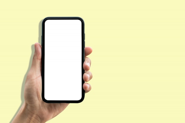 Hand holding smartphone on pastel yellow background