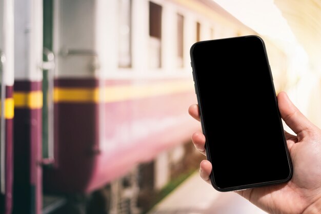 Hand holding smartphone in the train station