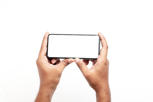 Hand holding a smartphone on a white surface.