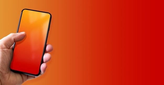 Hand holding a smartphone with blank red and orange screen Colorful horizontal banner