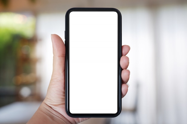 Hand holding smartphone with blank screen for app on cafe interior