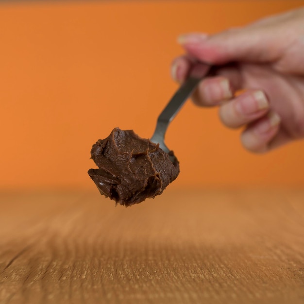 Hand holding a spoon of Brazillian chocolate sweet called Brigadeiro Vegan version